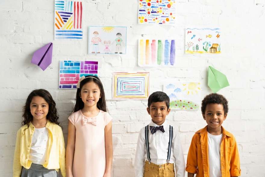 Children standing in front of their artwork on the playroom wall